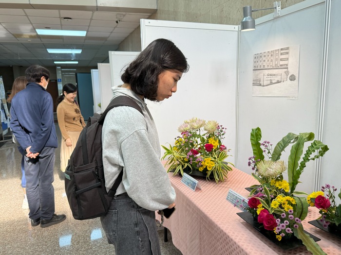 學生駐足欣賞花藝作品，展現通識課程結合美感教育與醫學人文的學習成果。圖片