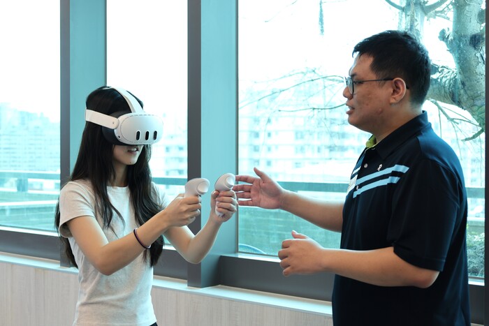 Professor Yu-Chi Cheng (right) from CSMU’s Department of Occupational Safety and Health guides students in experiencing the VR fall-prevention system.圖片