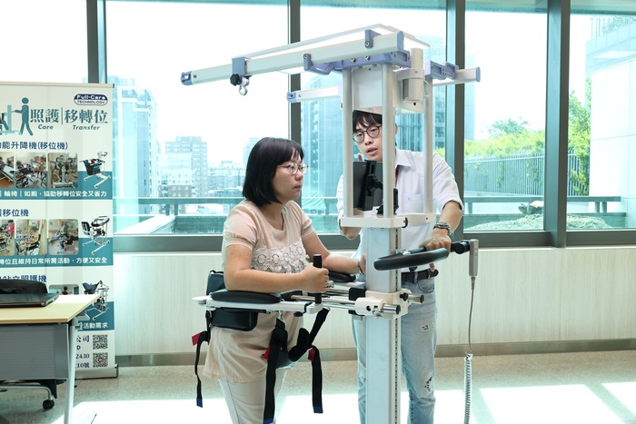 與會民眾體驗扶持步態訓練機，了解長者透過智慧輔助步行的感受。圖片